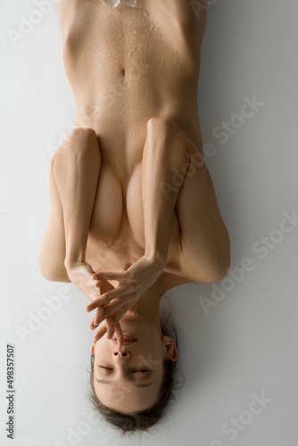 Top view of bare tranquil woman cover breast by hands with wet body