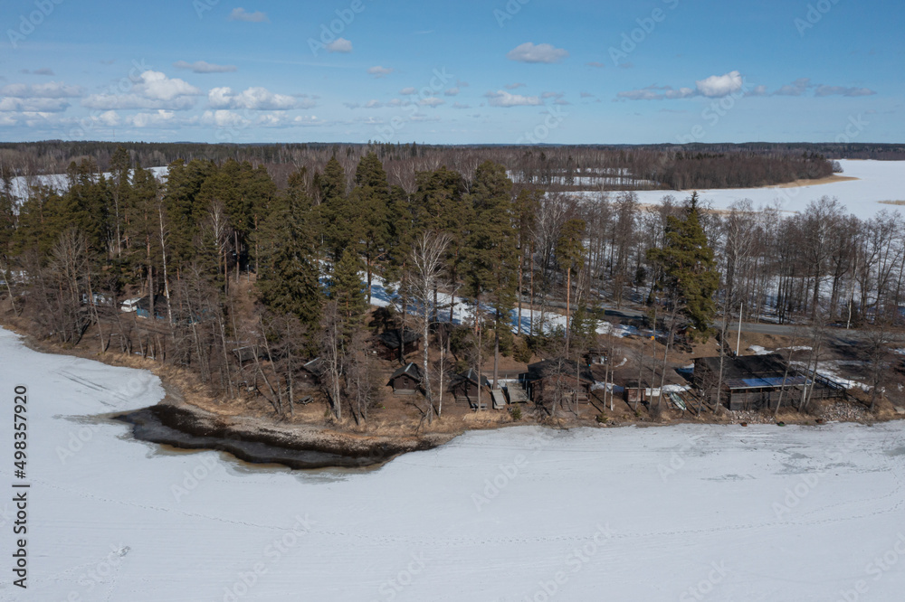 Landscape over a forest and a lake covered with ice and snow. Drone photo. Scandinavia. Finland.