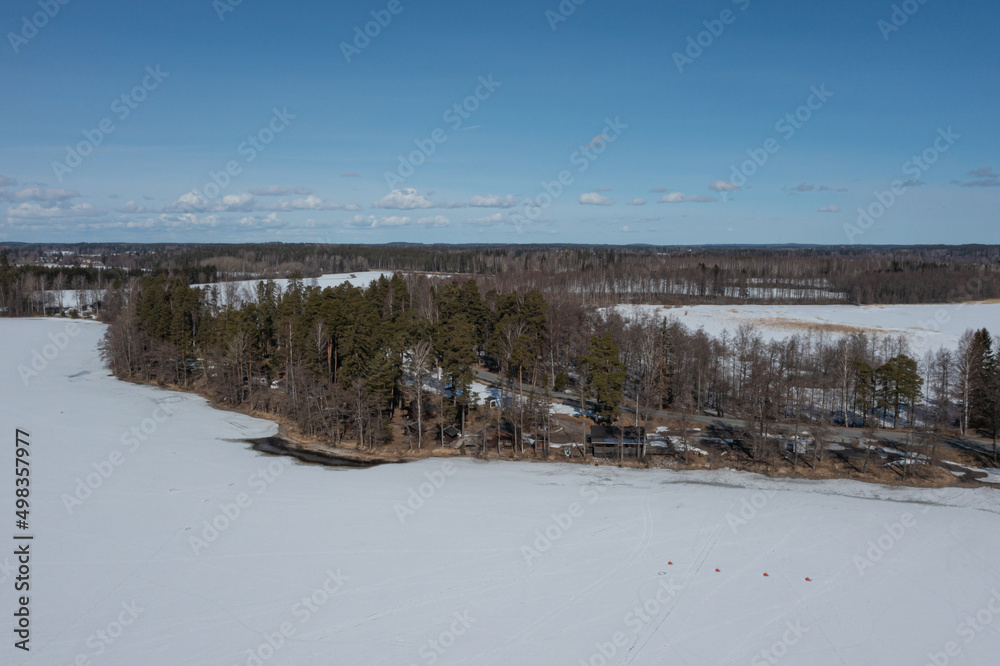 Landscape over a forest and a lake covered with ice and snow. Drone photo. Scandinavia. Finland. Landscape over a forest and a lake covered with ice and snow. Drone photo. Scandinavia. Finland.