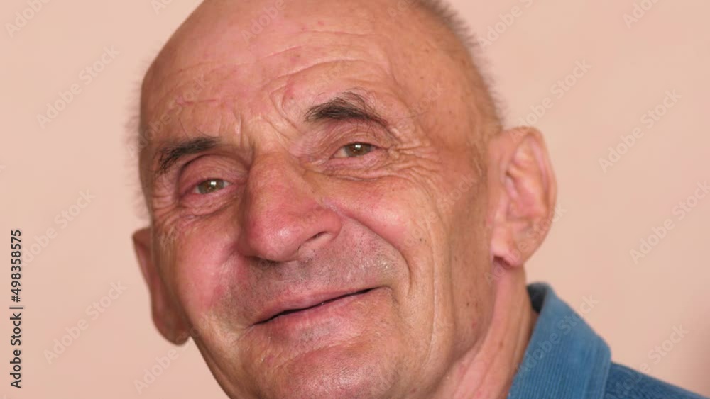 Portrait of caucasian senior man over 70 smiling looking at camera.Slow motion. Positive cheerful pensioner laughs while looking at the camera. Positive emotions. Real people. Retiree Theme Portrait of caucasian senior man over 70 smiling looking at camera.Slow motion. Positive cheerful pensioner laughs while looking at the camera. Positive emotions. Real people. Retiree Theme