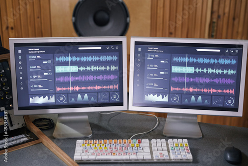 Background image of two computer screens with audio tracks in home recording studio, music production concept