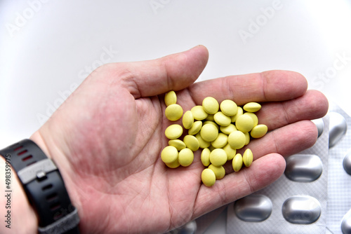 Yellow pills in the palm of your hand on a white background