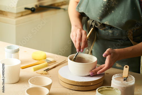 Slika na platnu Close-up of girl painting clay mug with glaze