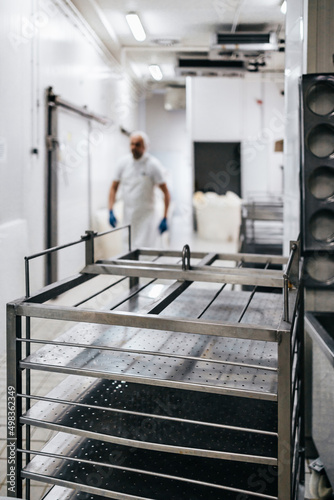 Manual worker in cheese and milk dairy production factory. Traditional European handmade healthy food manufacturing. Focus on foreground.