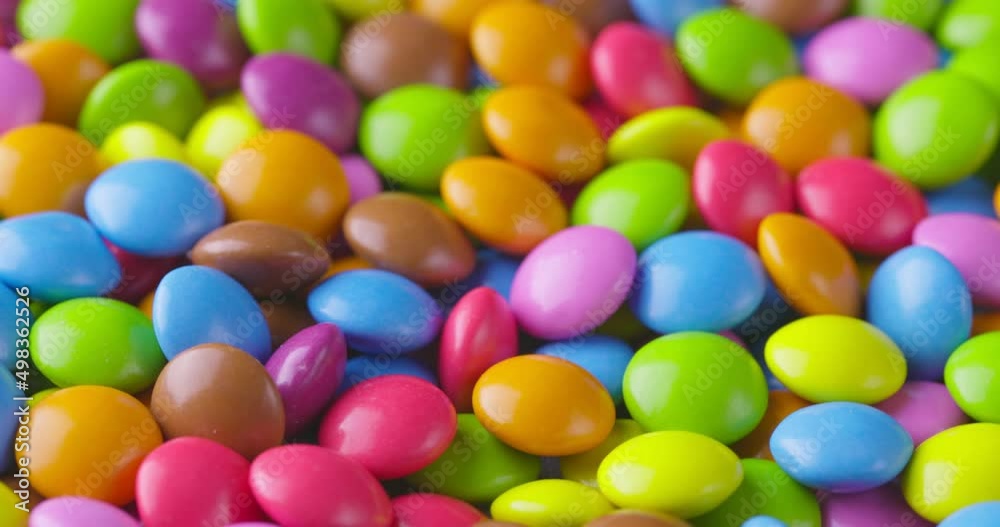 Slow motion close-up of round colorfull chocolate candies, dragee. Rotation and fall multicolored chocolate candies Slow motion close-up of round colorfull chocolate candies, dragee. Rotation and fall multicolored chocolate candies