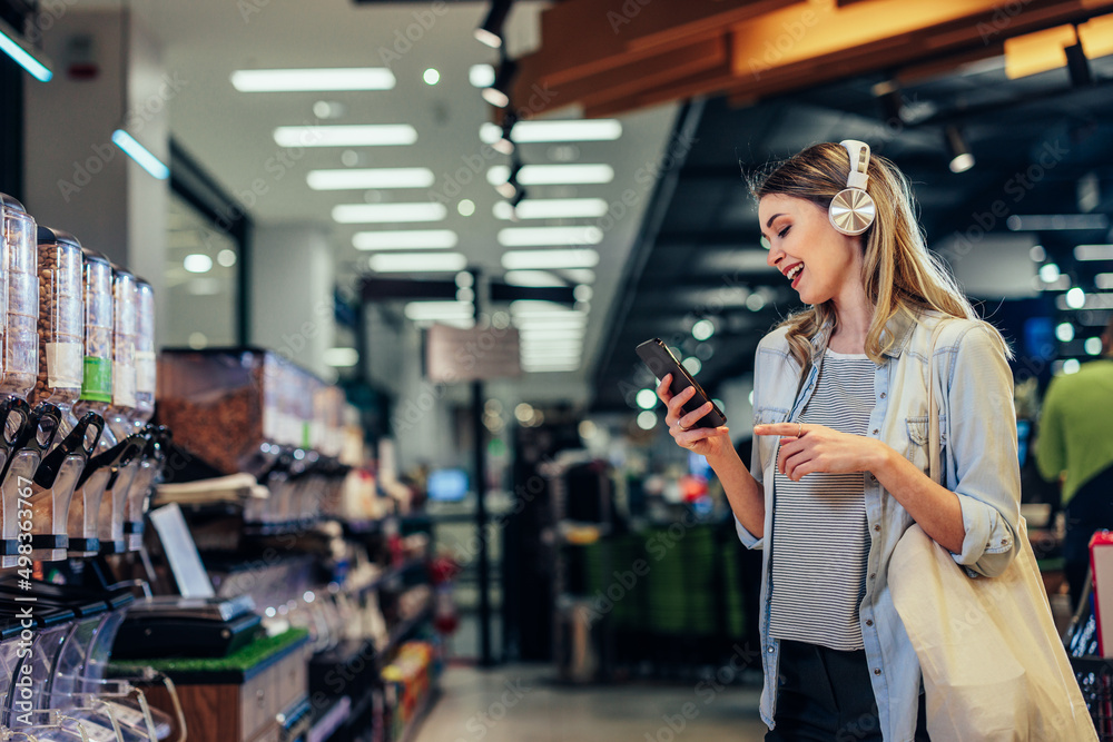 Young woman shopping in a grocery store and listening music Young woman shopping in a grocery store and listening music