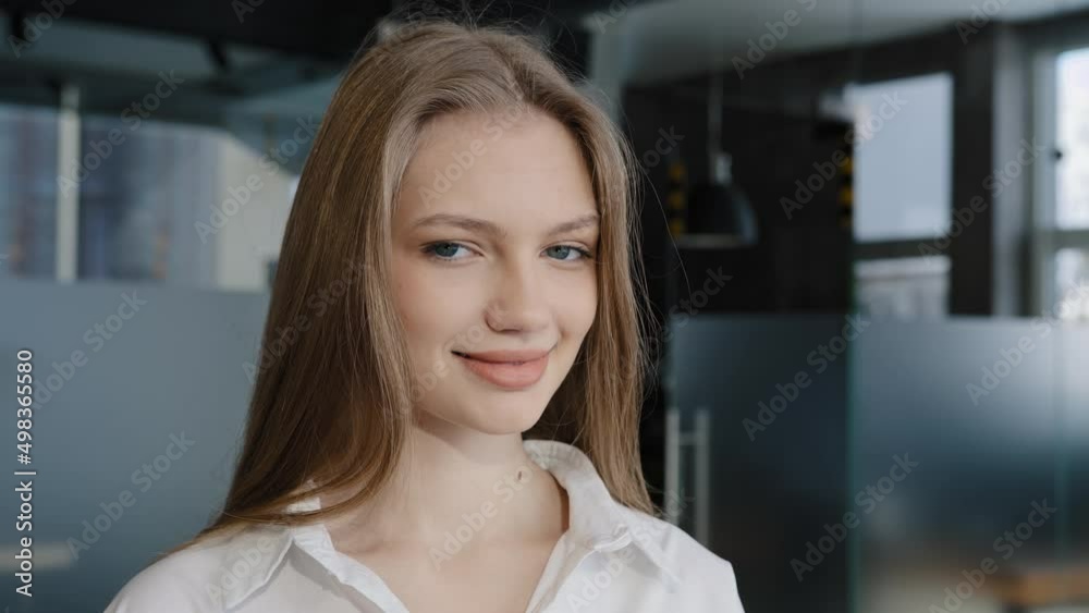 Portrait young pretty caucasian confident happy woman budding manager standing in office turning looking at camera smiling healthy white teeth elegant girl female student posing indoors natural beauty