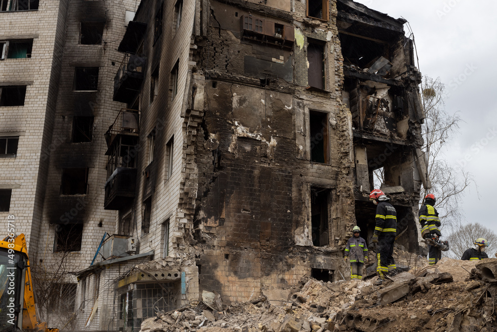 Bomberos trabajan en la limpieza de escombros y rescate de cuerpos de un edificio habitacional que fue destruido por un misil ruso en Bodoryanca Ucrania. - obrazy, fototapety, plakaty 
