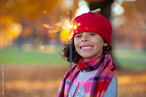 Autumn park scene with little girl holding a sparkler © bartsadowski