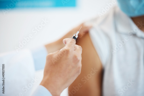 Are you ready. Cropped shot of an unrecognizable doctor injecting her patient with the Covid vaccine in her clinic.