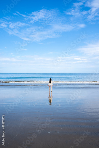 Holidays on the sea shore. Back view of a girl walking away on the beautiful tropical beach. Concept of relaxation and meditation