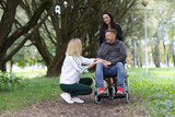 Two women and man in a wheelchair are talking in park