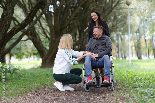 Two women and man in a wheelchair are talking in park