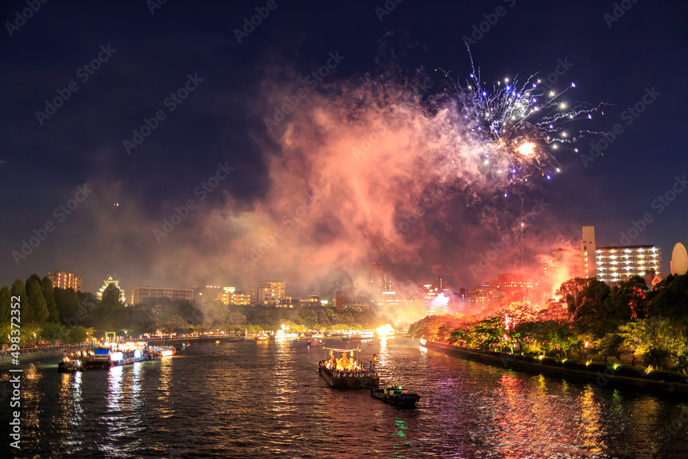 Fireworks explode over boats and crowds enjoying river festival at night