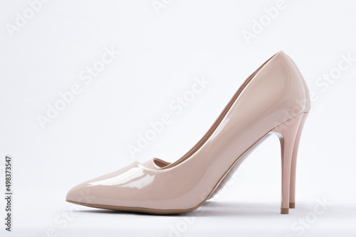 Elegant beige women's shoes with high heels. White background. Patent leather. Side view