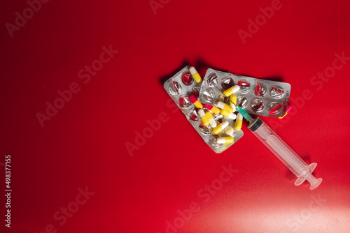 medical pills with srynge on red background