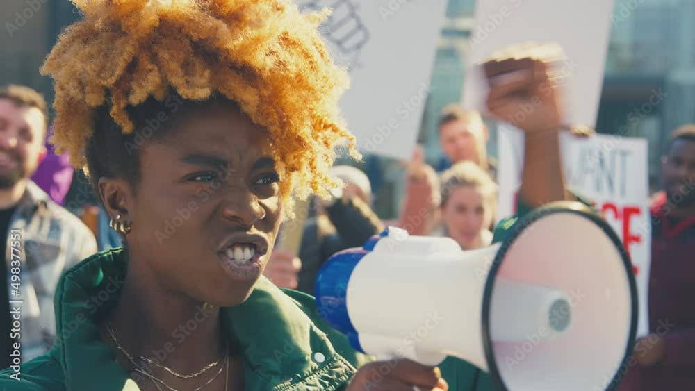 Group of protestors with megaphone holding placards and chanting slogans on demonstration march to promote black lives matter anti racist beliefs - shot in slow motion