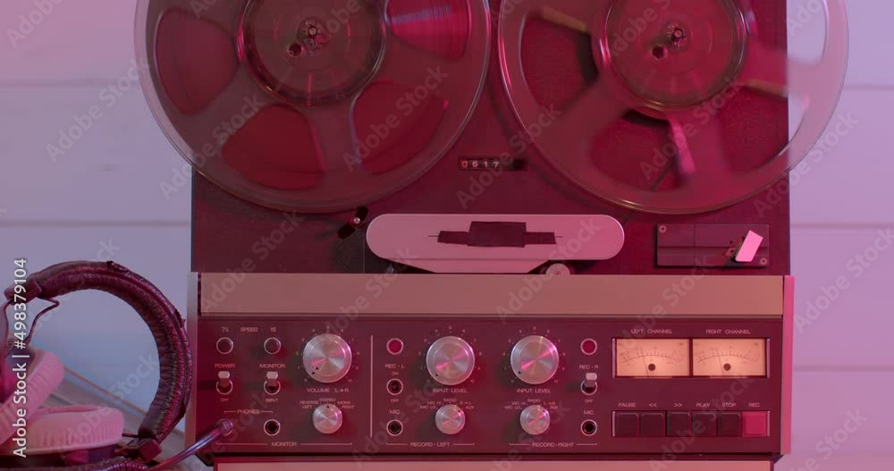 Retro reel to reel tape recorder playing in red light. Rotating vintage ...