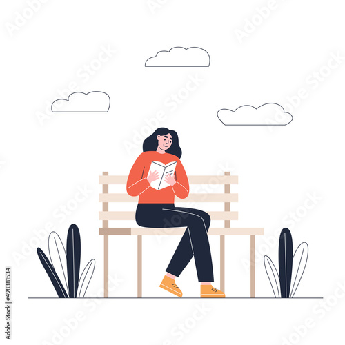 Young woman reading book on park bench