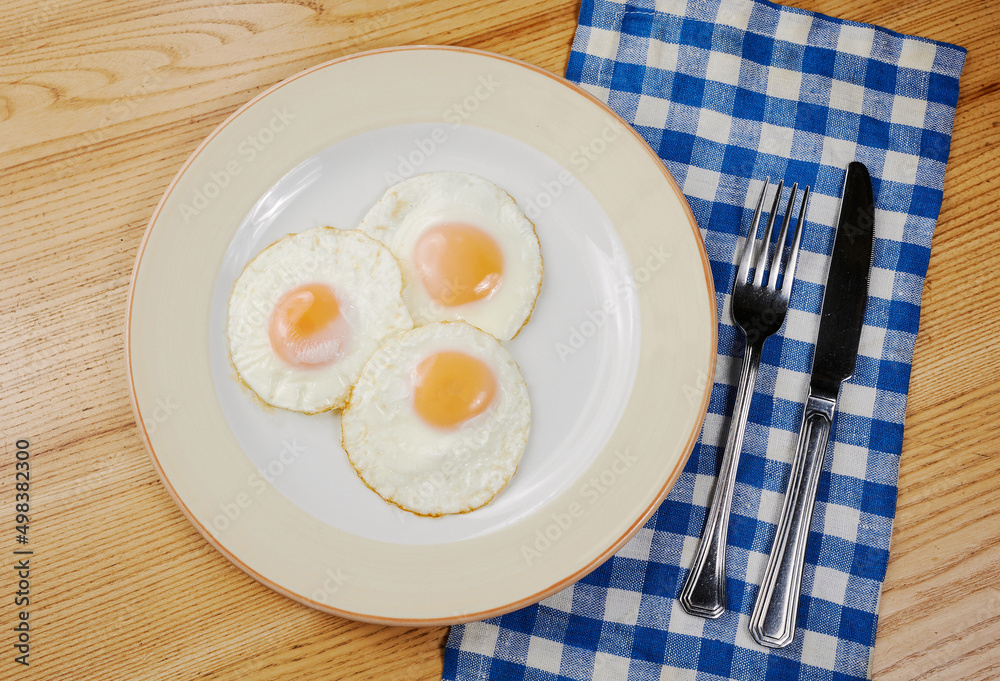 fried scrambled eggs from three eggs on a wooden table fried scrambled eggs from three eggs on a wooden table