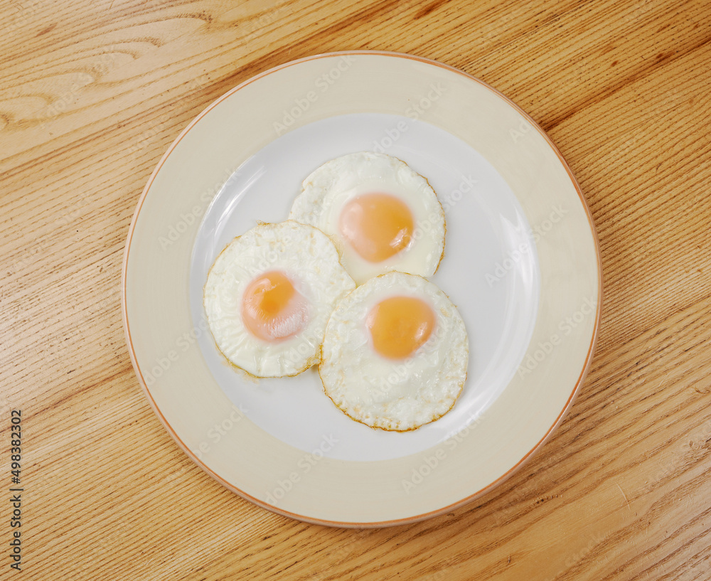 fried scrambled eggs from three eggs on a wooden table fried scrambled eggs from three eggs on a wooden table
