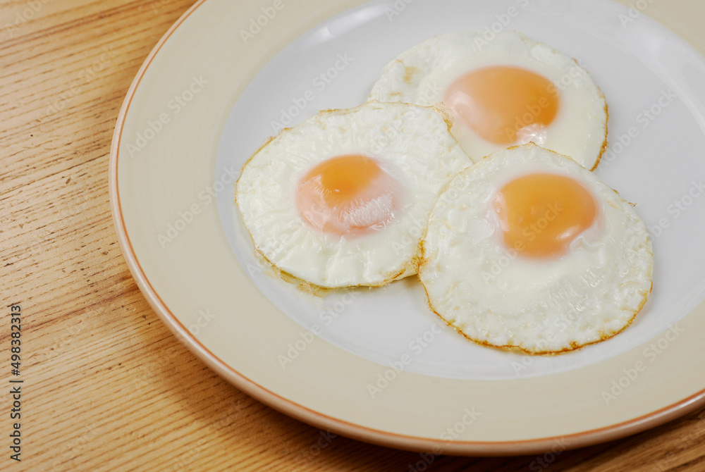 fried scrambled eggs from three eggs on a wooden table fried scrambled eggs from three eggs on a wooden table