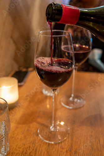 Pouring of dry Italian primitivo red wine in glass in Italian cantina restaurant in Puglia