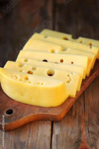 Selective focus. Macro. Cheese with holes slices on a wooden surface.