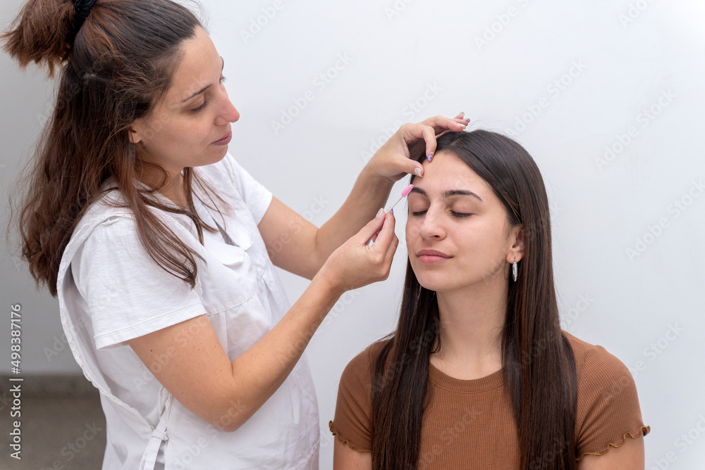 young woman performing a beauty session on the face, eyebrow shaping and eyelash service young woman performing a beauty session on the face, eyebrow shaping and eyelash service