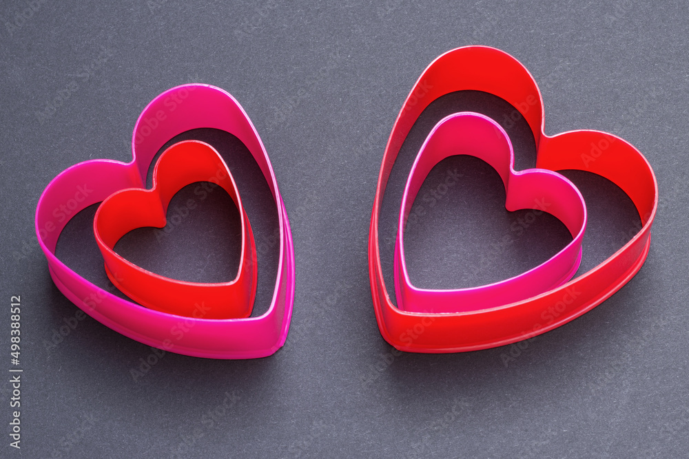 Heart-shaped plastic cookie cutters inside another heart. Love romantic concept