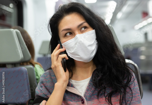 Woman traveler in a protective mask talking on a mobile phone in a subway car