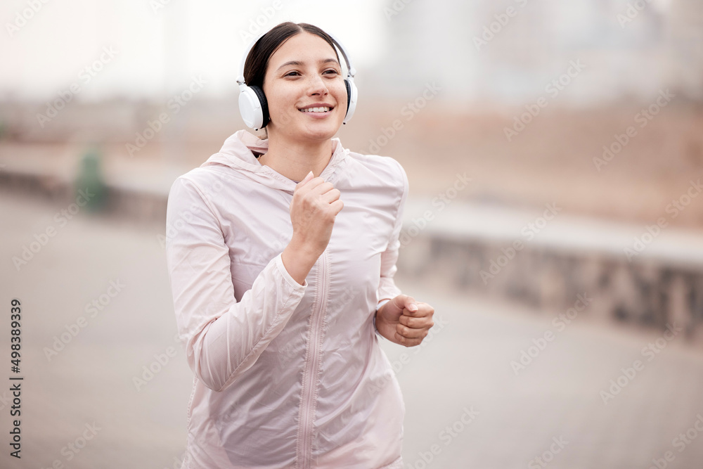 Good music, greater run. Shot of a young woman using headphones during her run on the promenade.