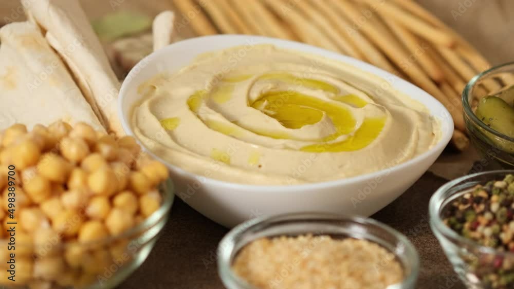 Chickpea hummus made from mashed chickpeas dip with tahini lemon garlic and olive oil close-up. Enjoying yummy hummus with pita, lavash, bread sticks, grissini. Kosher healthy vegan food. Lean dish Chickpea hummus made from mashed chickpeas dip with tahini lemon garlic and olive oil close-up. Enjoying yummy hummus with pita, lavash, bread sticks, grissini. Kosher healthy vegan food. Lean dish