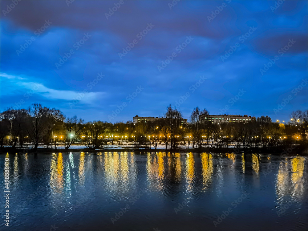 Landscape of resting park zone with pond in Moscow. Beautiful night view with lot of lights and reflections in water