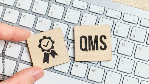 Acronym QMS or Quality Management System. Text with an icon on a piece of wood on the keyboard photo