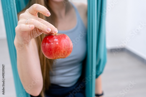 yogi fitness woman holds an apple after a workout in hammock for yoga. the concept of healthy eating and lifestyle