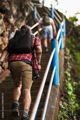 Making it to the top. Rearview shot of two men climbing stairs while hiking in the mountains.