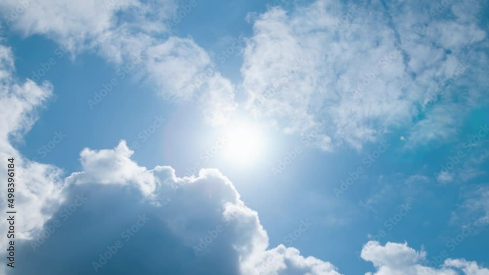 Low angle timelapse bright sun on blue summer sky with moving fluffy clouds, sun shining sunbeams, white cumulus clouds on sunshine day. Time-lapse, sun rays daylight, sunny cloudscape