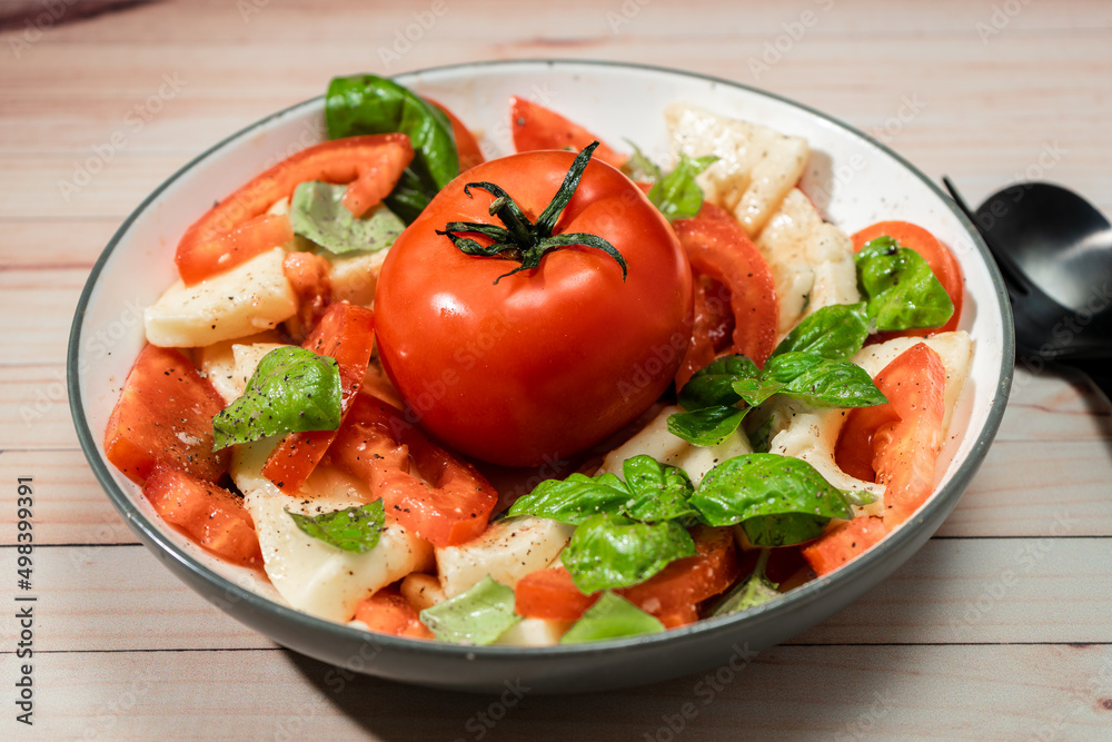 An Italian caprese salad of mozzarella, tomato and basil with olive oil and vinegar. An Italian caprese salad of mozzarella, tomato and basil with olive oil and vinegar.