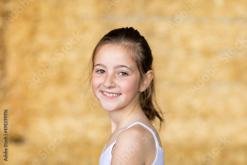 head and shoulders of young caucasian girl with hair tied back wearing white singlet photo