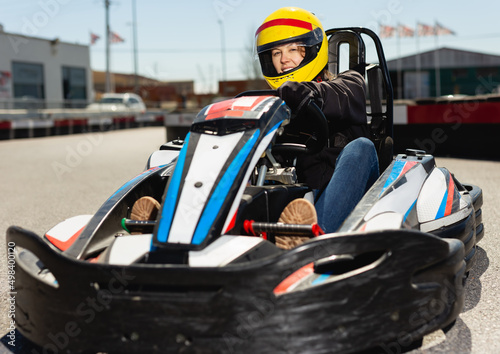 Portrait of girl in helmet driving a kart at racing track outdoors