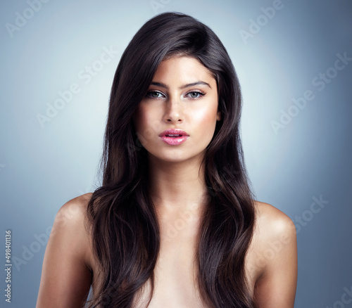 Her flawless beauty will rapture you. Studio shot of a beautiful young woman posing against a blue background.