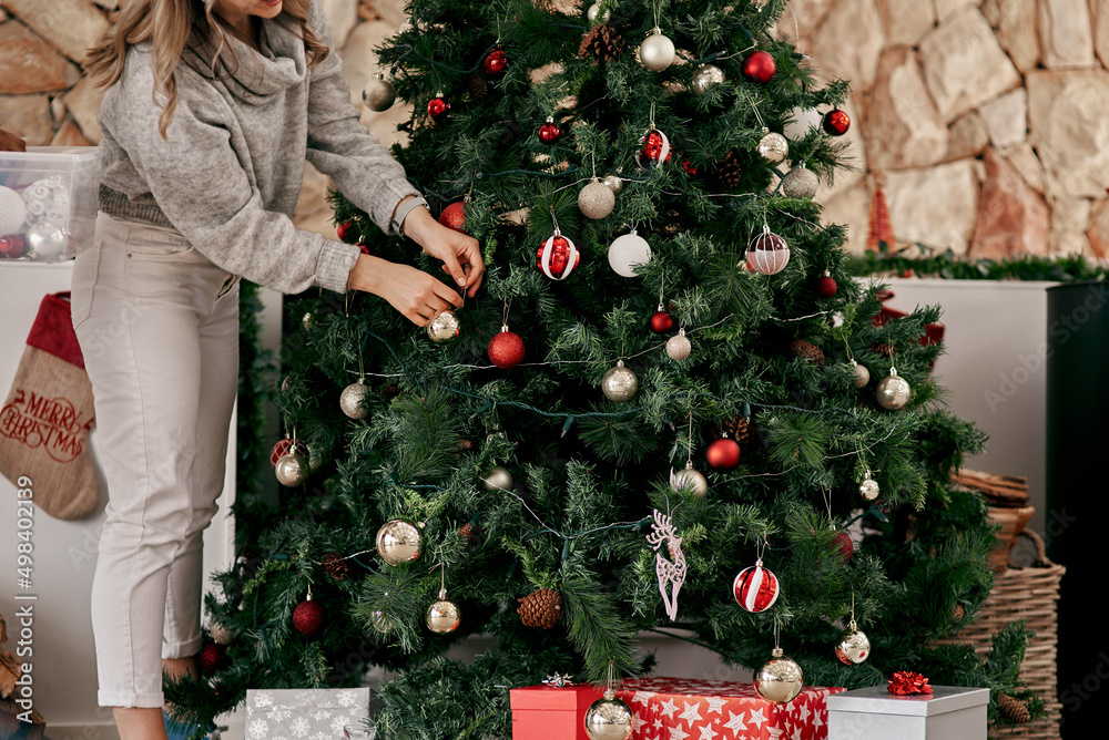 This should do the trick. Cropped shot of an unrecognizable woman placing decorations on a Christmas tree inside at home during the day.