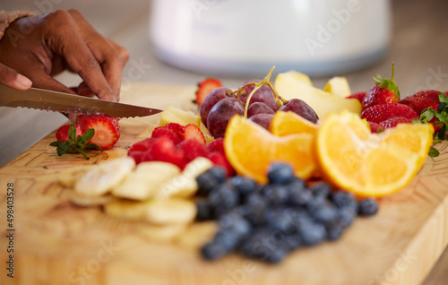 Preparing some healthy goodness to snack on. Closeup shot of an unrecognisable woman cutting fresh fruit at home. photo