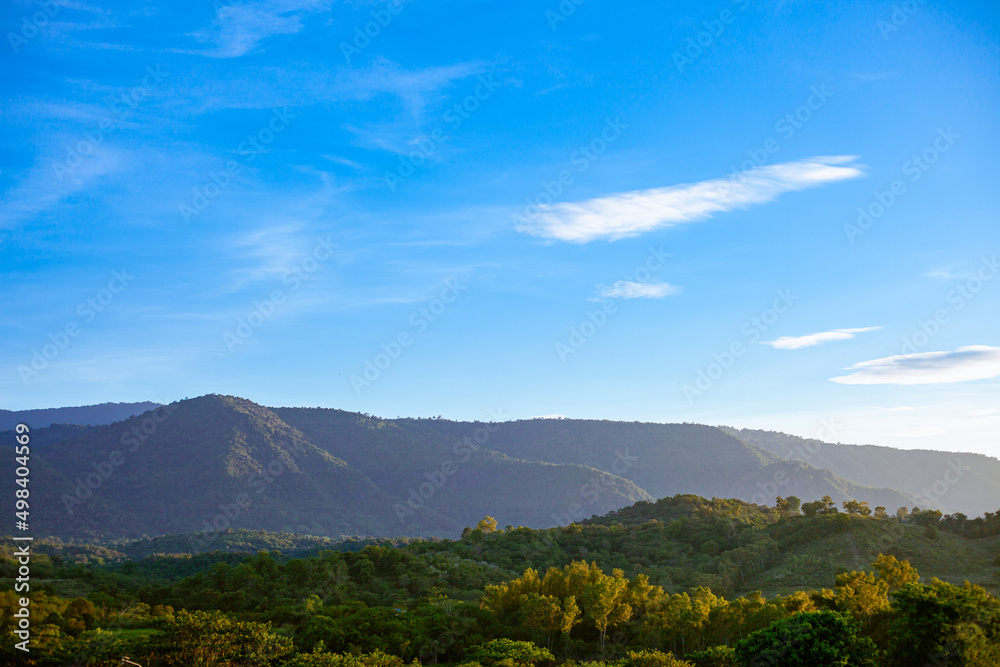 Mountains, flowers, grass and blue sky with white clouds. Background image for design. The concept of nature is bright. Mountains, flowers, grass and blue sky with white clouds. Background image for design. The concept of nature is bright.