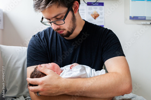 Young parent holding newborn baby in hospital maternity ward after delivery photo