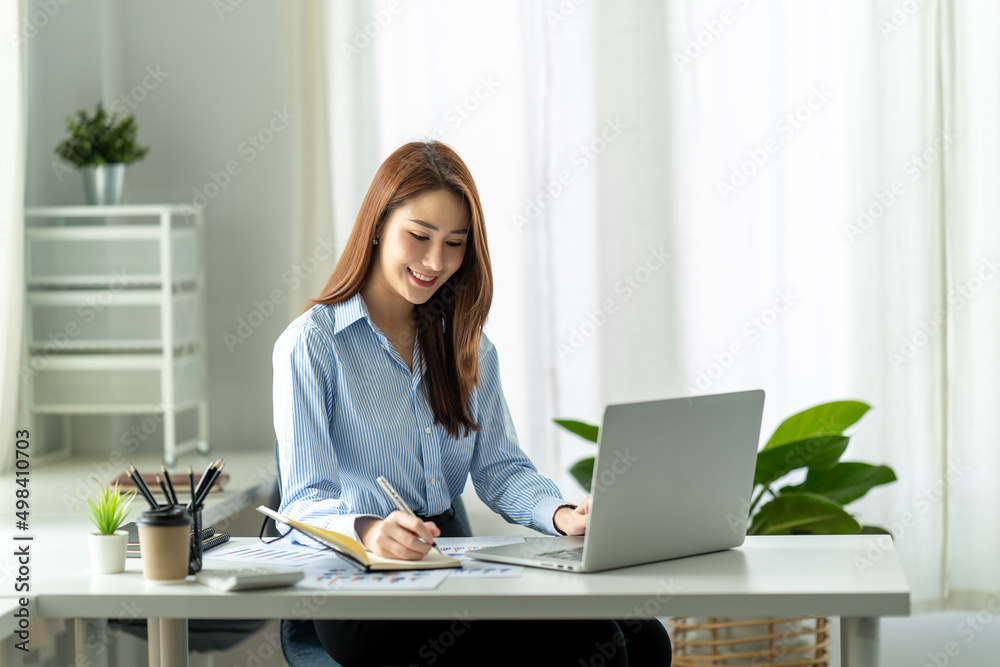 Beautiful young Asian girl working at a office space with a laptop. Concept of smart female business. Beautiful young Asian girl working at a office space with a laptop. Concept of smart female business.