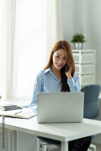 Asian businesswoman in formal suit in office happy and cheerful during using smartphone and working © PaeGAG