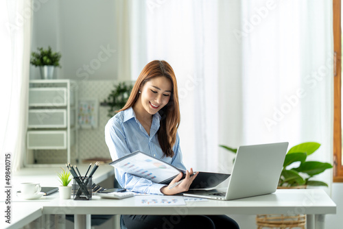 Young beautiful woman using her laptop while sitting in a chair at her working place.