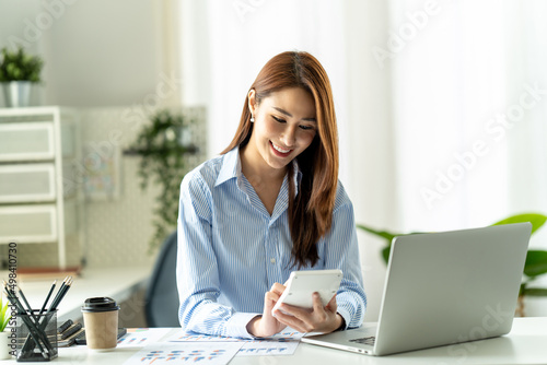 Portrait of Asian young female working on laptop and financial report at office.